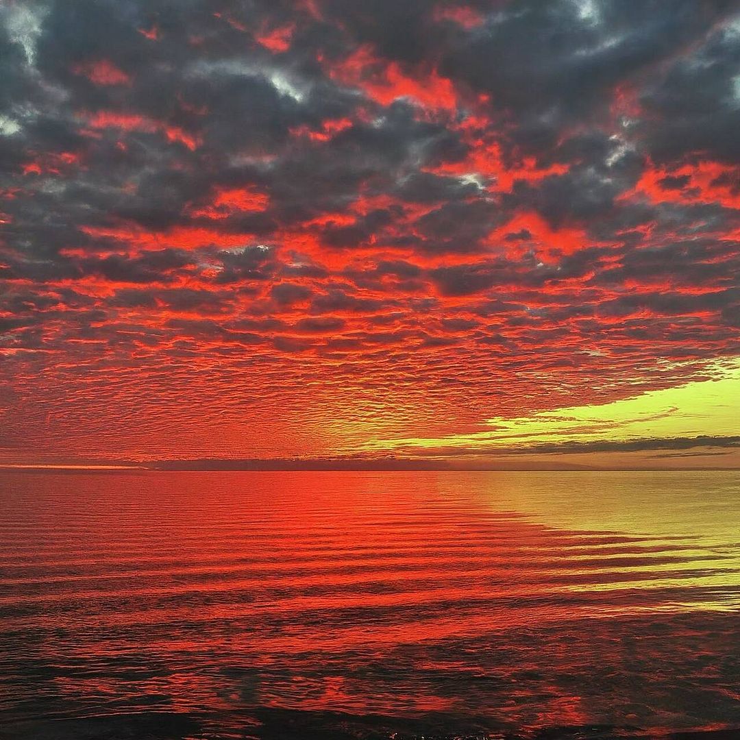 A red sky at sunset over a calm ocean.