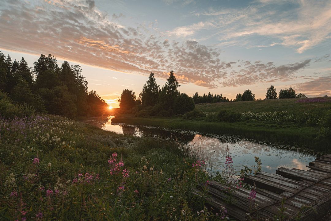 the sun is setting over a small river