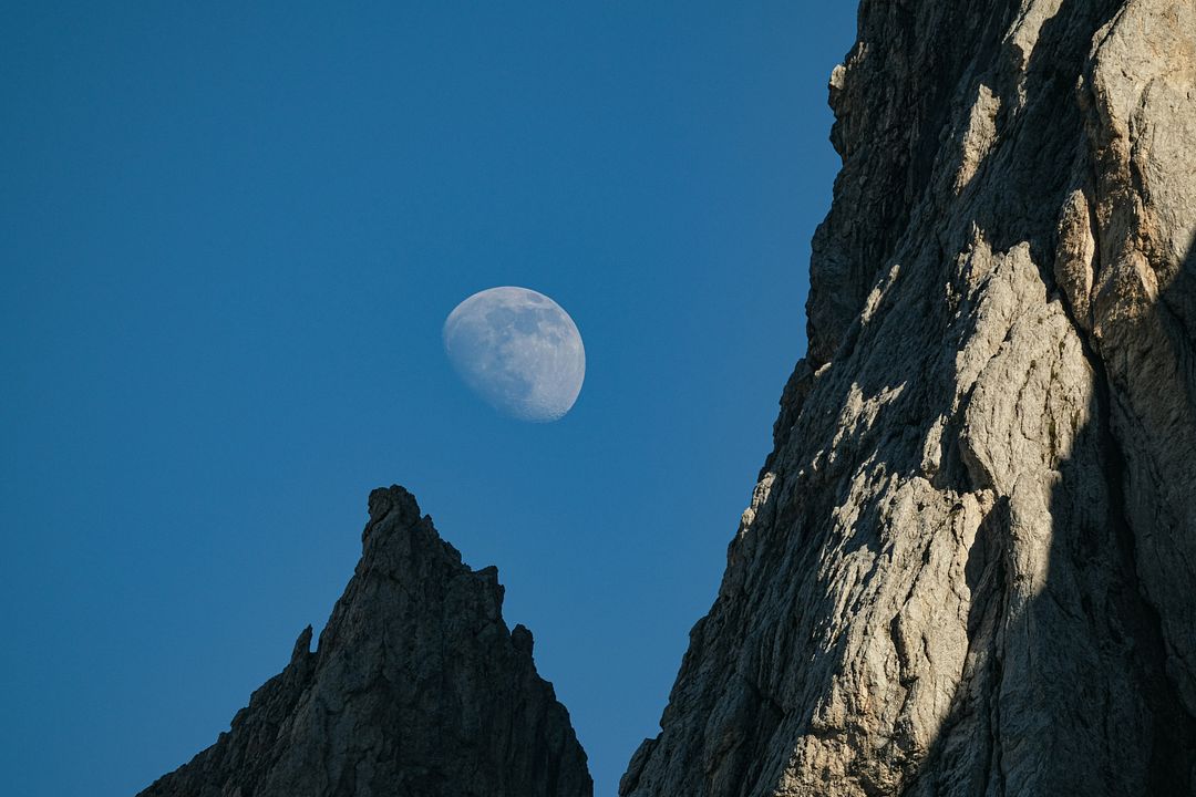 the moon is setting over the rocky mountains