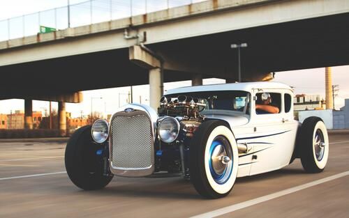 The image shows a white classic Ford Model A car with chrome elements.  Examples of hot rods based on the Ford Model A:  Russell Lowe's hot rod. The car is based on a frame from a Ford F-250 pickup truck. The body of the Ford Model A was complemented by the V12 Rover Meteor engine from the British Centurion tank. The engine capacity is 27 liters, it was supplemented with two Dominator carburettors and a 16-71 drive supercharger with a working pressure of six bar. In total, the engine produced 1000-1200 horsepower.  Jimmy Herwethen's hot rod. Almost all the work was done manually. A chassis with a 104-inch wheelbase was prepared. The frame was expanded by 3 inches and received a 10-inch height change at the rear. The project used springs and longitudinal suspension arms from Ford '36 in conjunction with the Winters rear axle and John's Industries 9-inch finned drum brakes made of aluminum.  Hot rod "Marauder". The body is a model of a 1929 Ford pickup truck. The chassis of the car was custom-made, reinforced and reinforced in eight places. The front part of the new Mustang has been adapted for pneumatic cylinders, and the rear axle is a Mustang 8.8 with 31 slots with a high—friction differential, 4 longitudinal levers and a Panar thrust. The engine is a Cummins 5.9 12v diesel, directly from a Daf truck. The starter and alternator were converted to 12 volts instead of 24