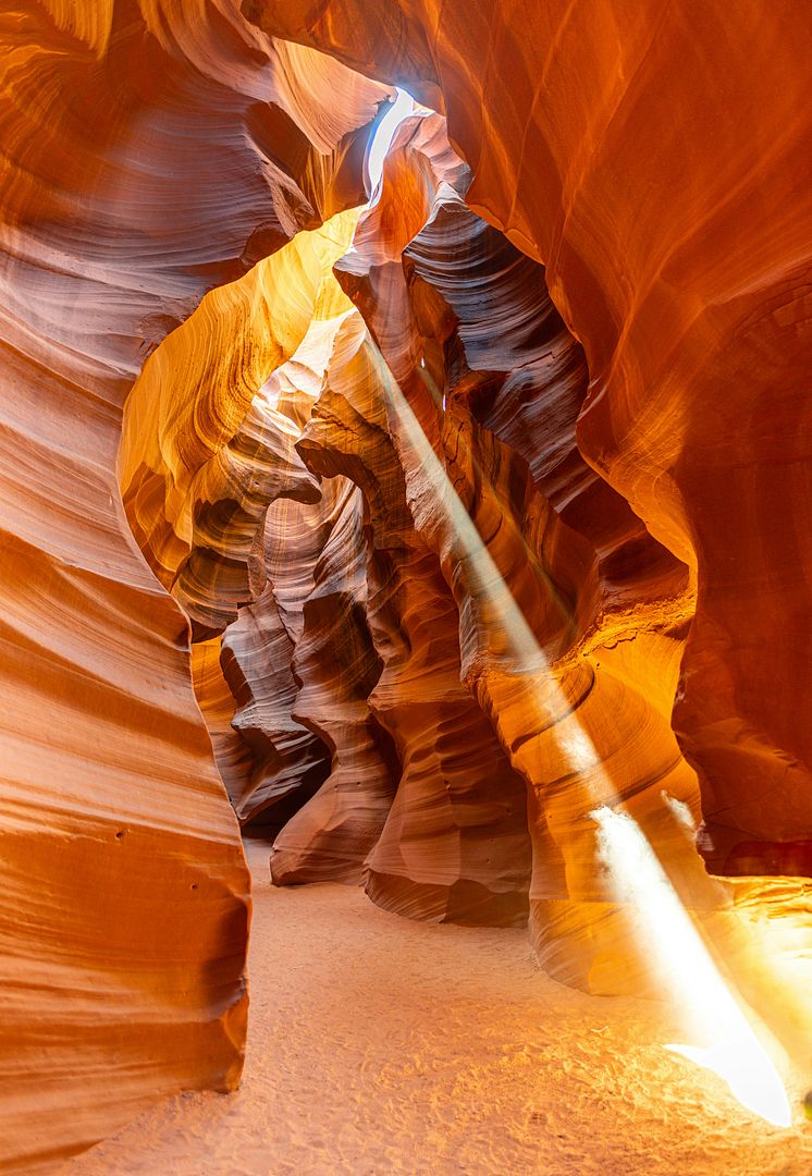 A mesmerizing sunbeam illuminates the winding, vibrant sandstone walls of Upper Antelope Canyon.