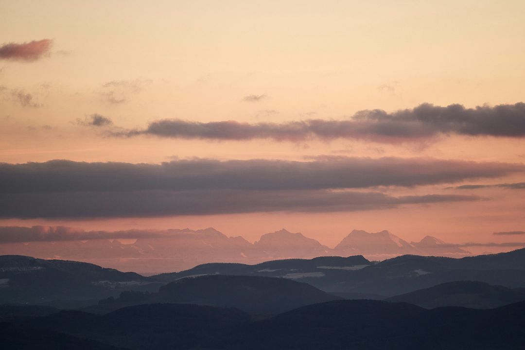 a plane flying over a mountain range at sunset