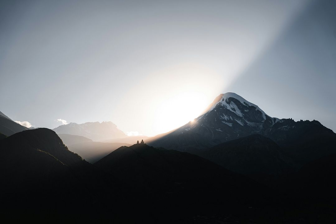 the sun is shining through the clouds over the mountains