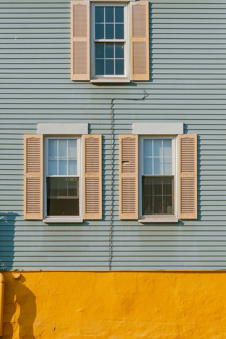 a yellow fire hydrant in front of a blue house