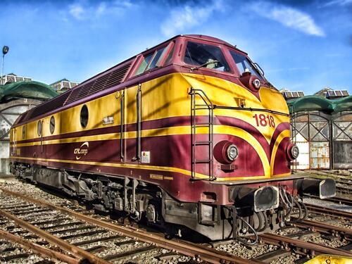 The image shows a TEP60 diesel locomotive with a red and yellow color at a railway station.  TEP60 is a passenger six—axle diesel locomotive with direct current electric transmission, produced in the USSR at the Kolomna Locomotive Plant from 1960 to 1987.   It was produced in two versions — single-section and two-section. A total of 1,241 single-section TEP60 diesel locomotives and 116 two-section 2TEP60 locomotives were built.   During the 1970s and 1980s, TEP60 locomotives were the main passenger locomotives on the railways of the USSR, but then they began to be decommissioned.   For its time, the TEP60 was the fastest diesel locomotive in the world, with a speed of 193 km/h.