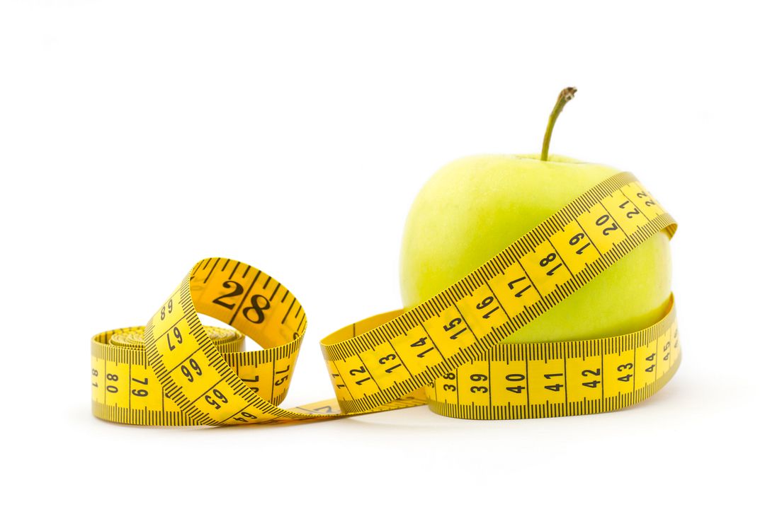 Green apple with measuring tape isolated on white background