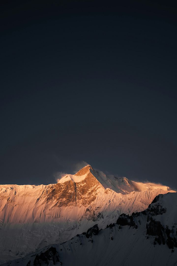 a large mountain covered in snow under a dark sky