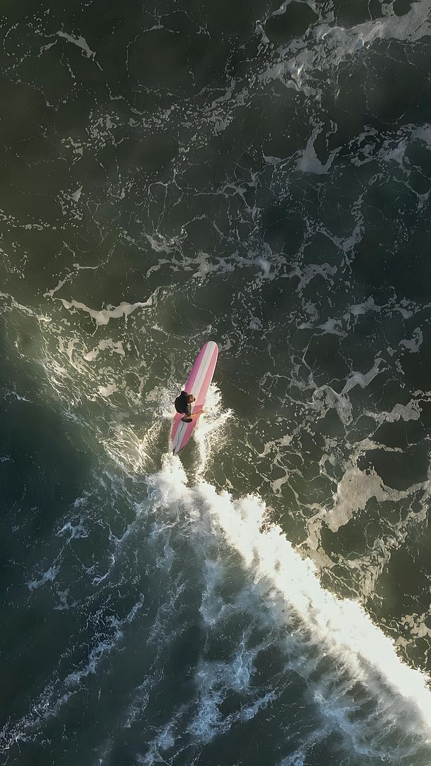 Surfing with a pink surfboard